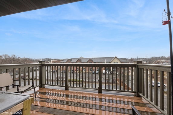 View from a balcony overlooking adjacent buildings and a parking area.
