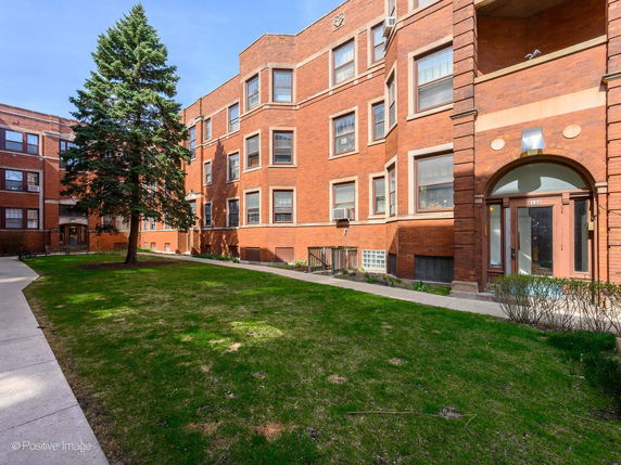 Front view of a multi-story brick apartment building with multiple windows and entrance doors.