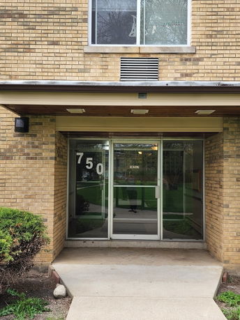 Front view of a brick building entrance with glass doors.