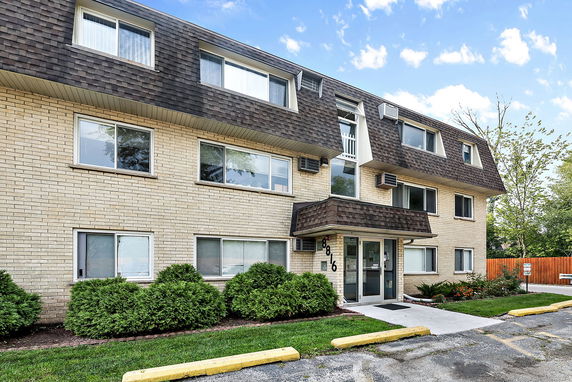 Front view of a three-story apartment building with a brick facade and multiple windows.