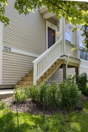 Front view of a house with a wooden staircase leading to a porch and entrance door.
