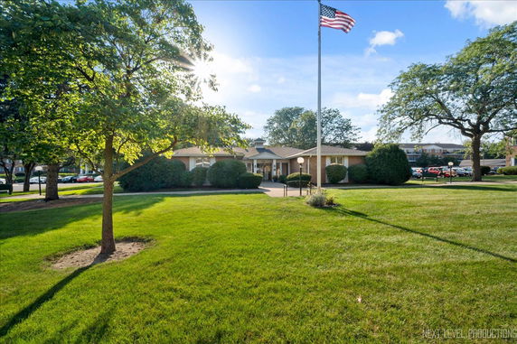 Front view of a single-story building with a flagpole and a well-maintained lawn.
