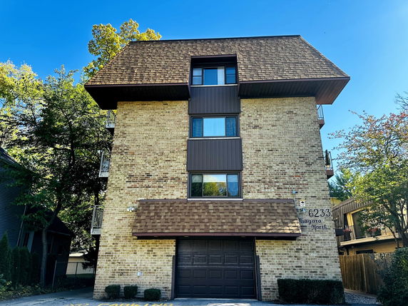 Front view of a multi-story building with a brick exterior and a garage door.