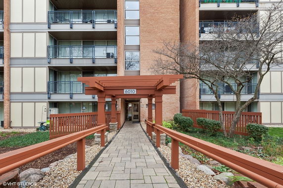 Front view of a multi-story building with balconies and landscaped walkway.