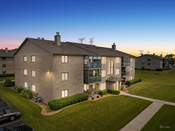 Exterior view of a multi-story brick apartment building at dusk.