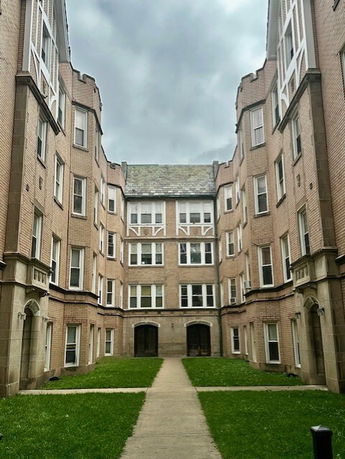 Front view of a multi-story brick apartment building with symmetrical design and multiple windows.