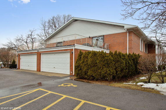 Front view of a brick house with a double garage and a balcony.