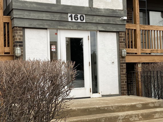 Front view of a building entrance with a glass door and number 160 above it.