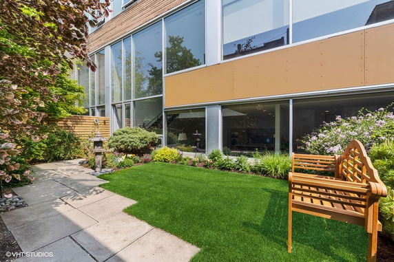 Front view of a modern building with large windows and a small landscaped garden area.