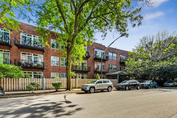 Front view of a brick apartment building with balconies and large windows.
