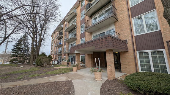 Front view of a multi-story brick apartment building with balconies.
