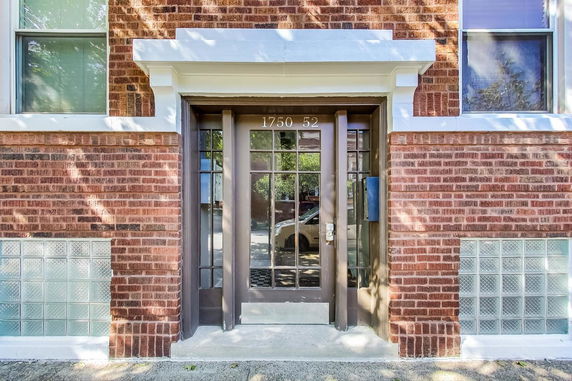 Front view of a building entrance with a glass door and brick exterior.