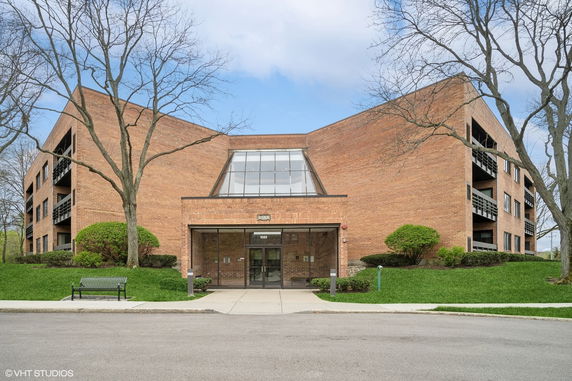 Front view of a multi-story brick building with large glass entrance.