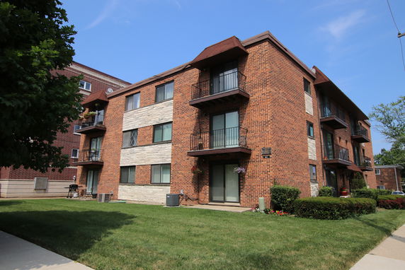 Front view of a multi-story brick apartment building with balconies.