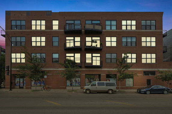 Front view of a multi-story brick building with balconies and large windows.
