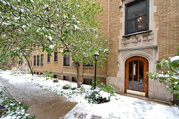 Front view of a brick building with arched doorway in a snowy setting.