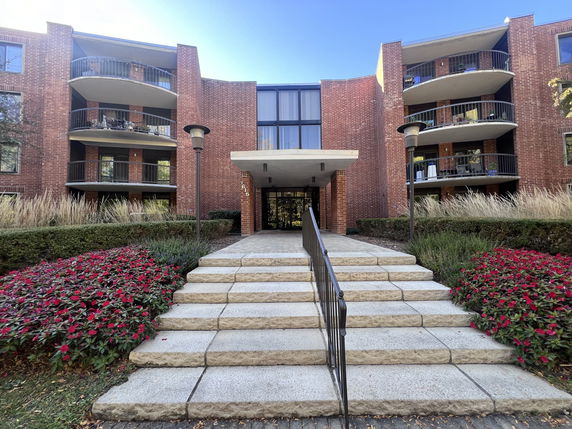 Front view of a multi-story brick building with balconies and a central entrance.