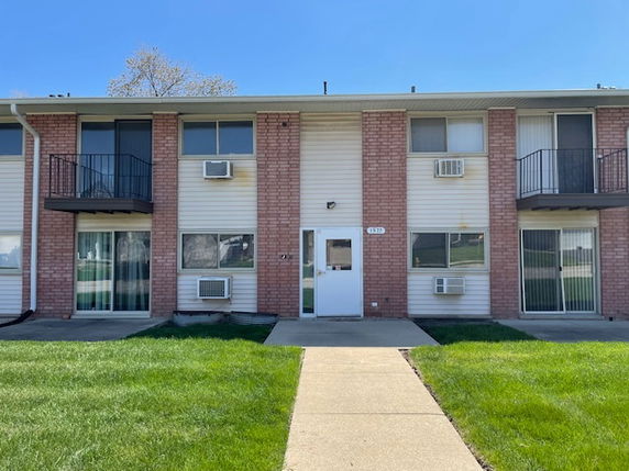 Front view of a two-story apartment complex with balconies and central entrance.