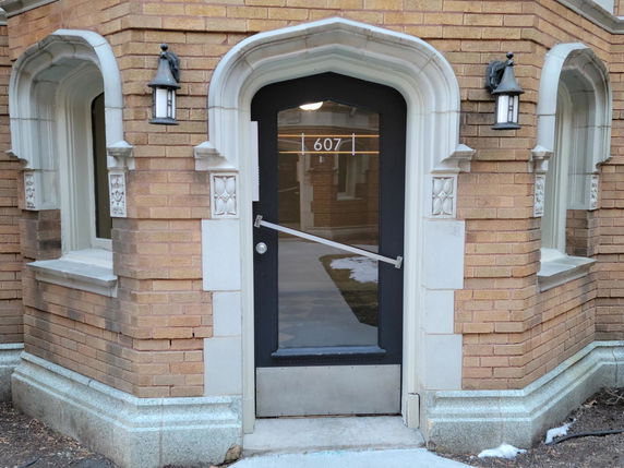 Front view of a building entrance with decorative brickwork and arched windows.