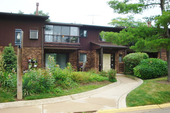 Front view of a two-story house with a brick facade and wood siding.