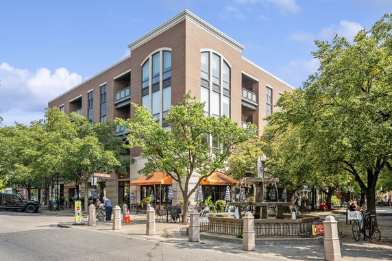Front view of a multi-story commercial building with large windows and outdoor seating area.