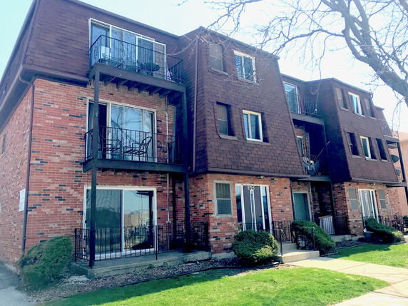Front view of a three-story apartment building with brick exterior and small balconies.