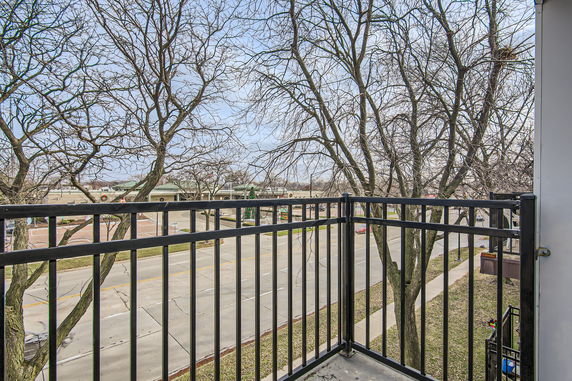 View from a balcony overlooking a street with bare trees and buildings in the distance.