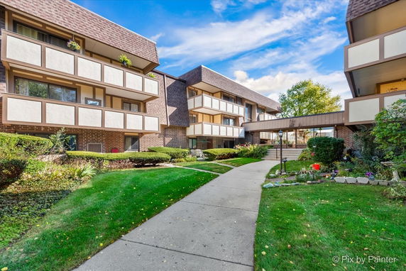 Front view of a multi-story building with balconies and a walkway.