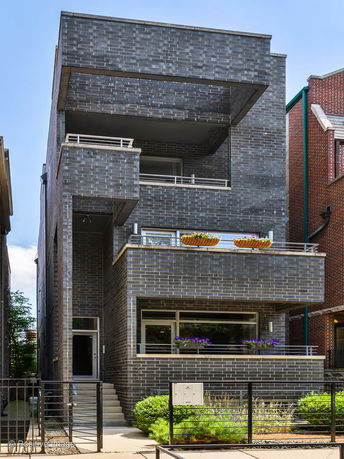 Front view of a modern multi-story house with dark brick exterior and balconies.
