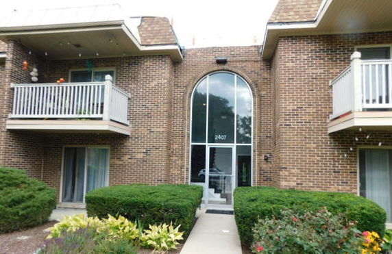 Front view of a two-story brick building with balconies and large central glass entrance.