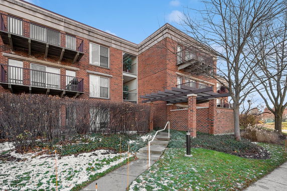 Front view of a brick apartment building with balconies and a covered entrance.