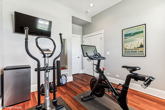 Home gym area with exercise equipment and a wall-mounted TV.