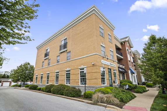 Front view of a multi-story brick building with commercial spaces on the ground floor.
