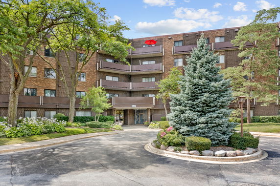Front view of a multi-story brick apartment building with balconies.