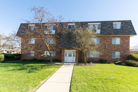 Front view of a multi-story brick building with a sloped roof.