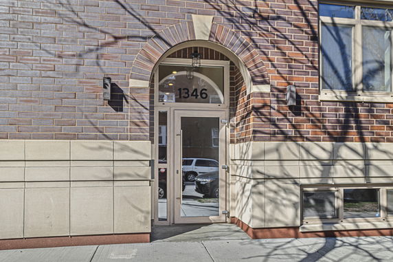 Front view of a brick building entrance with arched doorway.