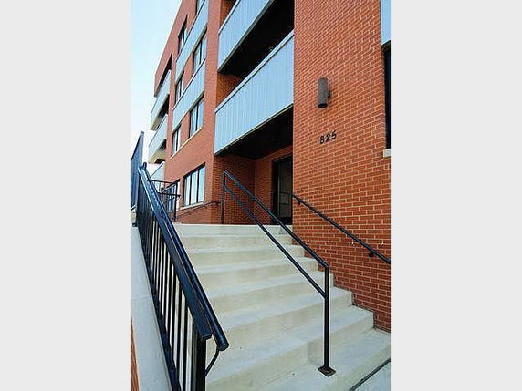 Front view of a multi-story building with brick facade and stairs leading to the entrance.