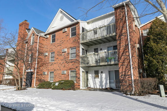 Front view of a three-story brick apartment building with balconies.