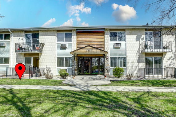 Front view of a two-story apartment building with balconies and a central entrance.