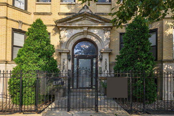 Front view of a building with ornate entrance and wrought iron gate.
