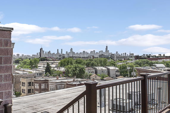 Panoramic view of a city skyline with buildings, trees, and rooftops in the foreground.