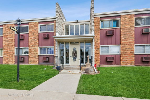 Front view of a multi-story brick apartment building with entryway.