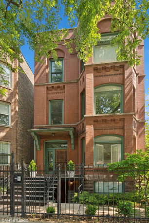Front view of a multi-story red brick building with large windows.