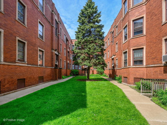 Front view of a multi-story brick apartment building surrounding a courtyard.