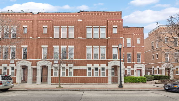 Front view of a three-story brick building with multiple windows and arched doorways.