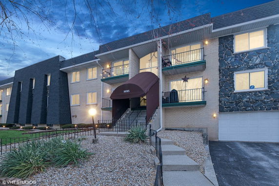 Front view of a multi-story building with balconies and entrance canopy.