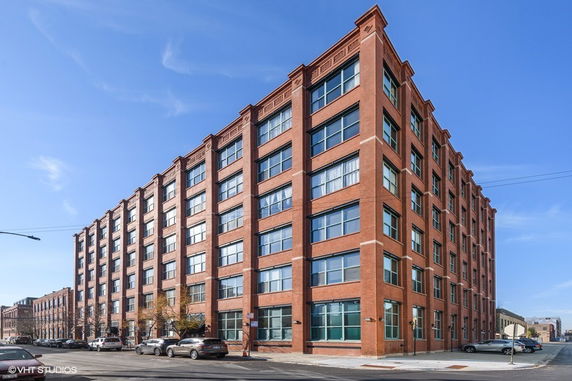 Front view of a multi-story brick building with large windows.