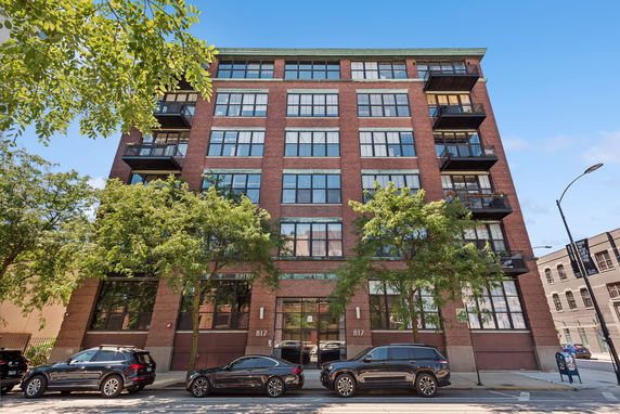 Front view of a multi-story brick building with large windows and balconies.