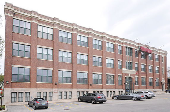 Front view of a large three-story brick building with multiple windows.