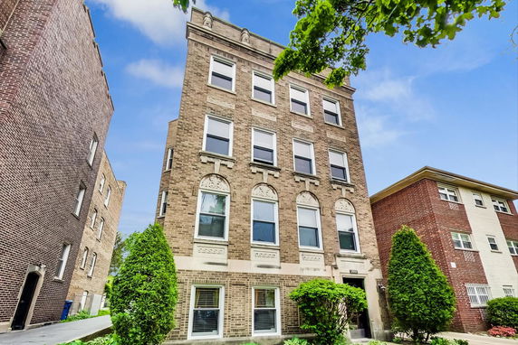 Front view of a multi-story brick building with decorative stonework around the windows.